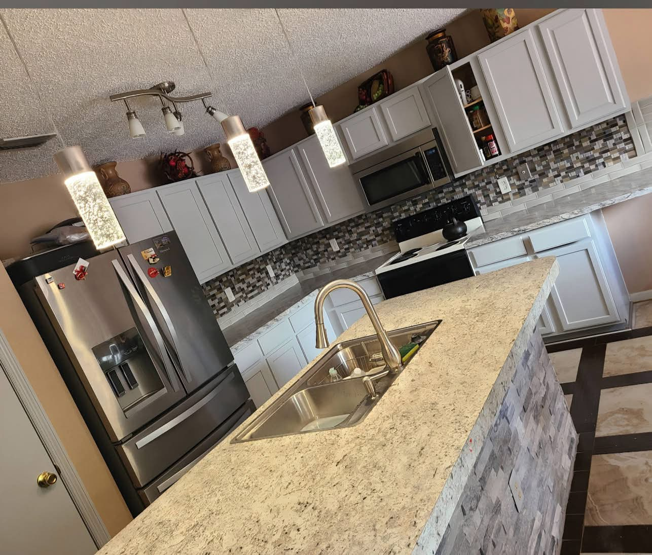 Kitchen with painted cabinets, mosaic backsplash, granite island and stacked stone