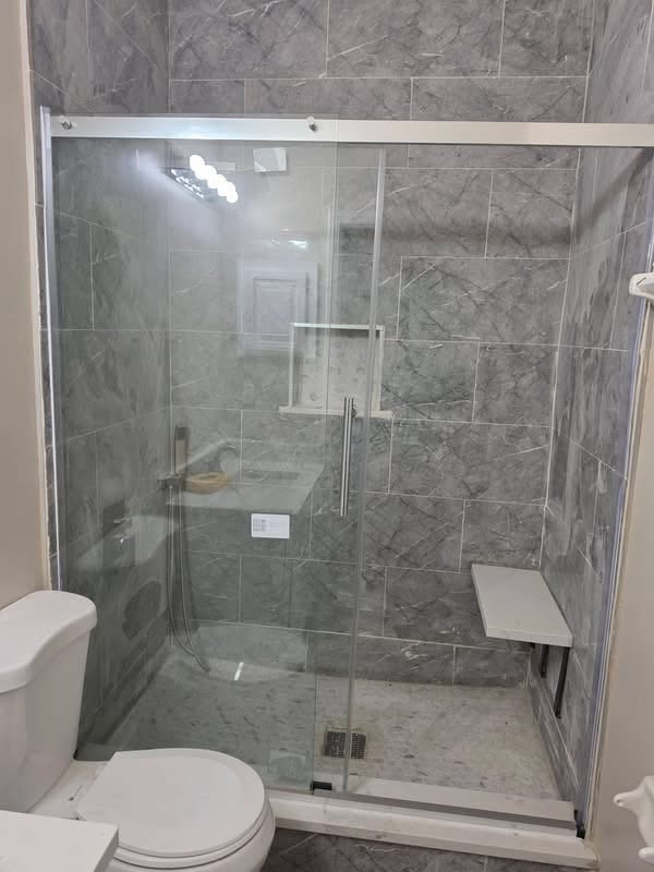 Gray marble-look tile shower with sliding glass door and bench